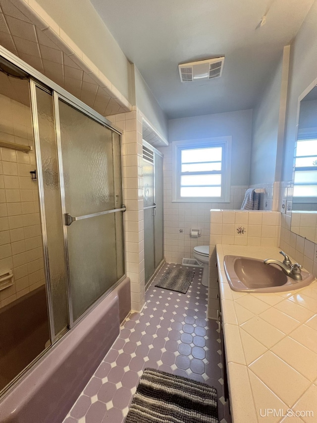 bathroom featuring vanity, visible vents, tile walls, toilet, and tile patterned floors