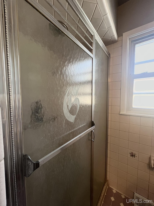 full bath with tile walls and a shower stall