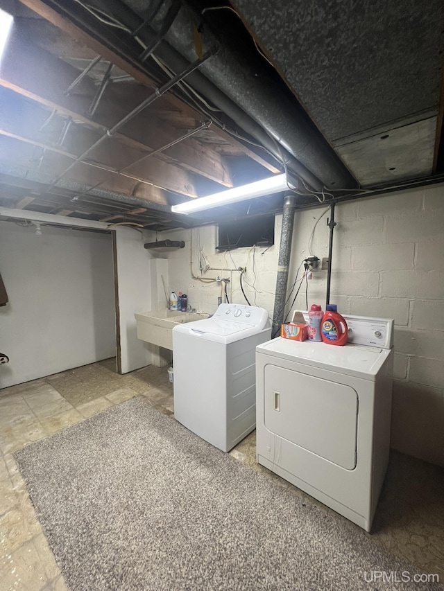 unfinished below grade area featuring washing machine and dryer and a sink