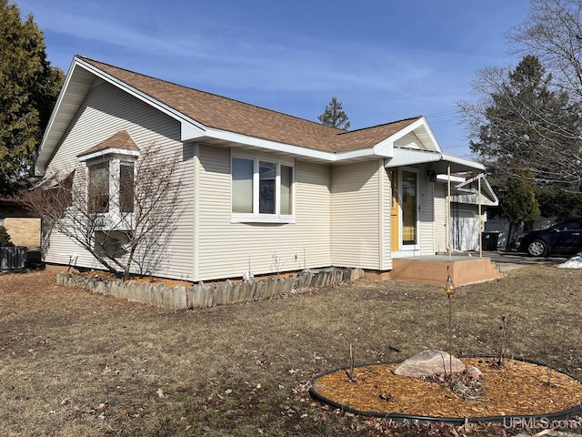 view of front facade featuring central AC unit and a shingled roof