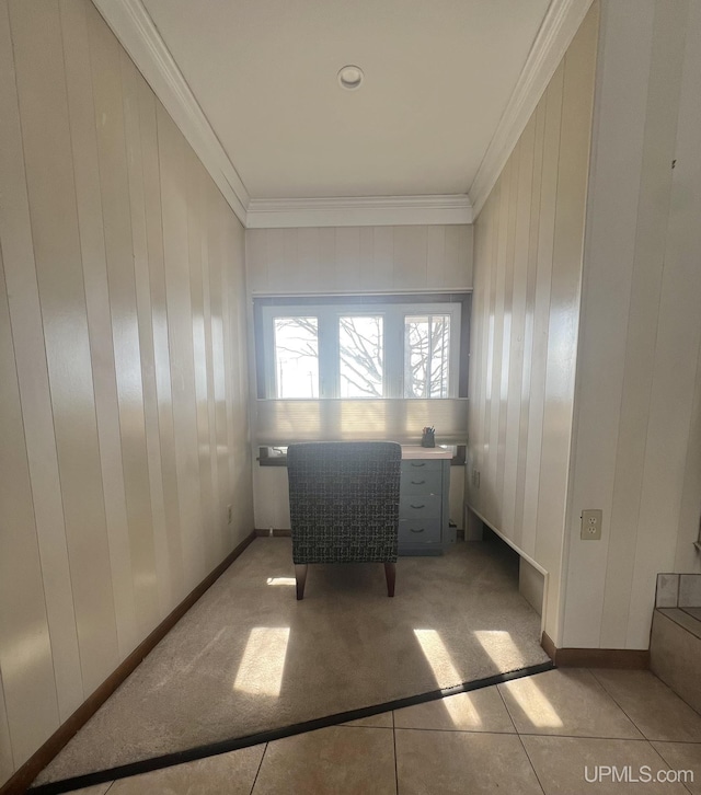 interior space featuring light tile patterned floors, wooden walls, baseboards, and ornamental molding