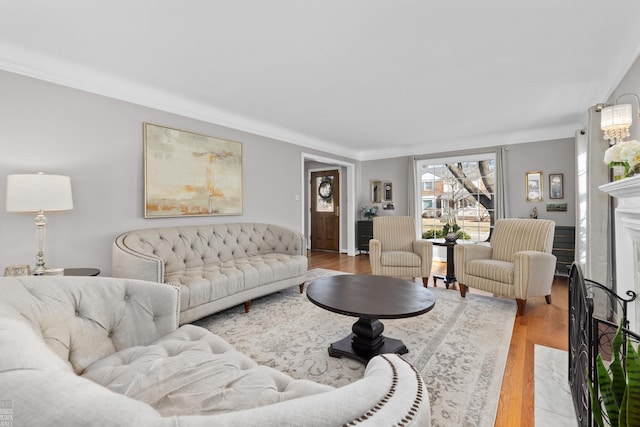 living room with a high end fireplace, ornamental molding, and wood finished floors