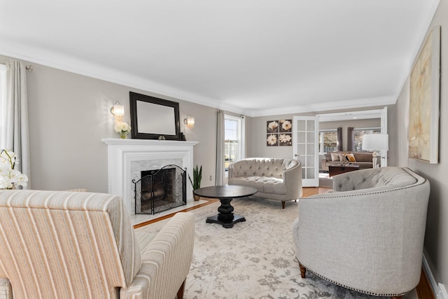 living area featuring a high end fireplace, french doors, crown molding, and wood finished floors