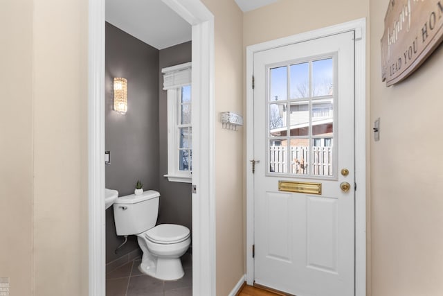 bathroom featuring baseboards, toilet, and tile patterned flooring