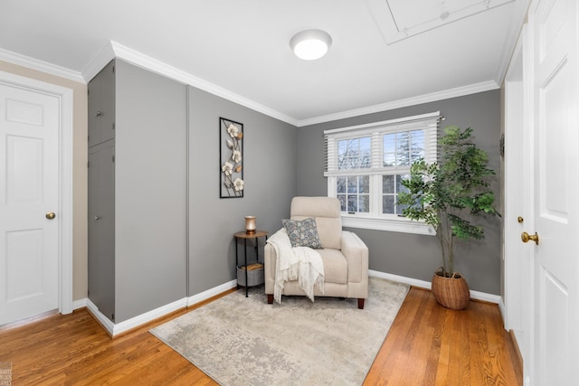 sitting room featuring attic access, crown molding, baseboards, and wood finished floors