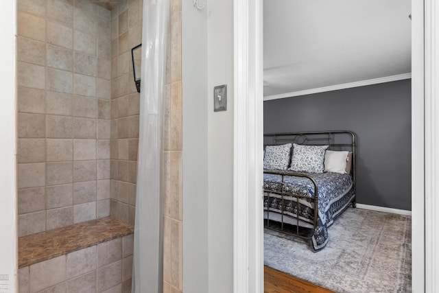 full bathroom with tiled shower, crown molding, and baseboards