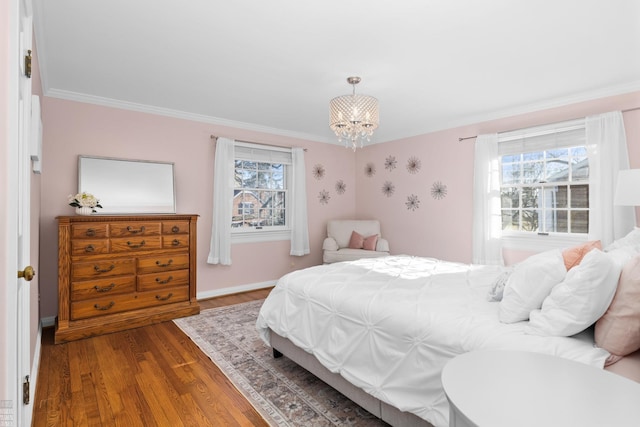 bedroom featuring baseboards, crown molding, an inviting chandelier, and wood finished floors