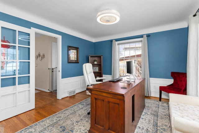 office with visible vents, wainscoting, and wood finished floors