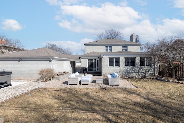 rear view of property with a yard, an outdoor hangout area, brick siding, and a chimney