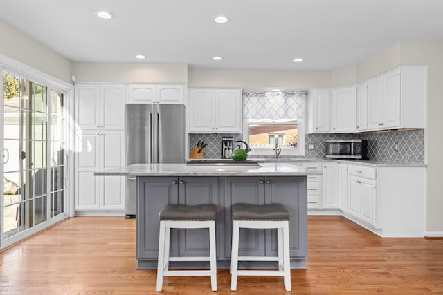 kitchen with a kitchen bar, appliances with stainless steel finishes, light wood-style flooring, and a center island