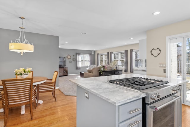 kitchen featuring high end stove, light wood-style flooring, gray cabinets, a center island, and recessed lighting