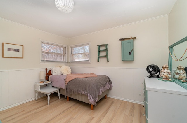 bedroom featuring light wood-style flooring, wainscoting, and ornamental molding