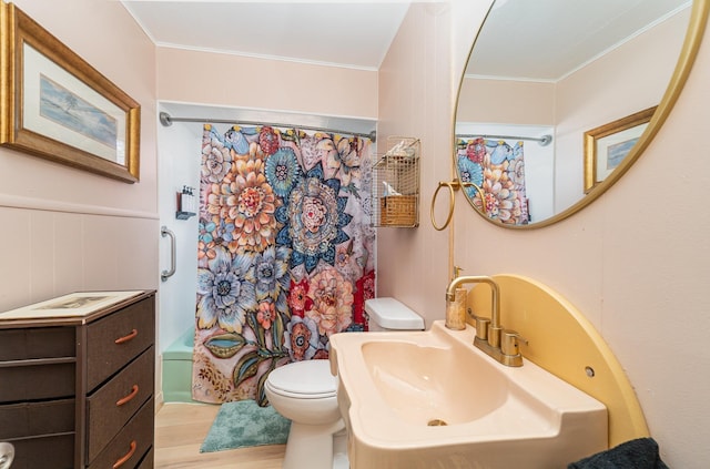 bathroom with wood finished floors, shower / bath combo, a sink, crown molding, and toilet