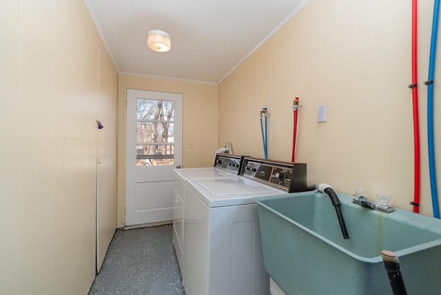 washroom with laundry area, crown molding, washing machine and dryer, and a sink