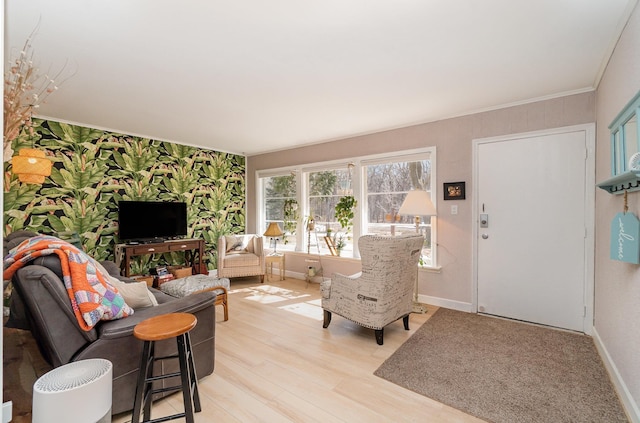 living room featuring light wood finished floors, wallpapered walls, an accent wall, and baseboards