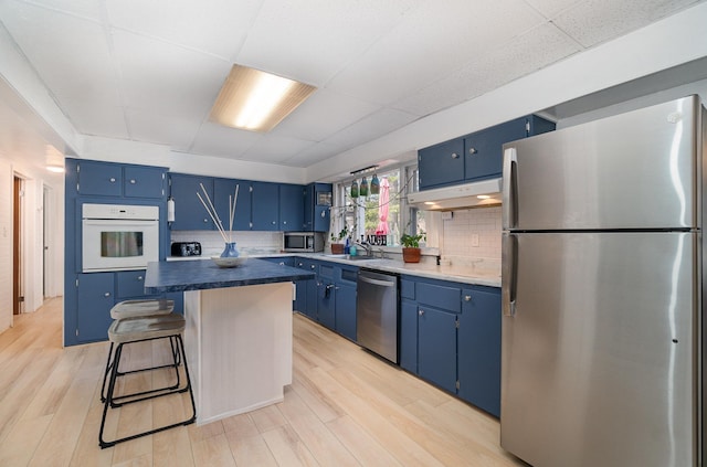 kitchen featuring appliances with stainless steel finishes, a kitchen island, blue cabinets, and light wood-style floors