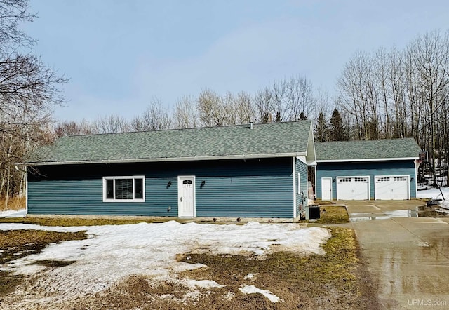 snow covered garage with cooling unit and concrete driveway