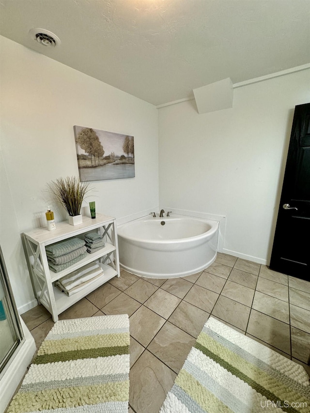 full bathroom featuring tile patterned flooring, a bath, baseboards, and visible vents