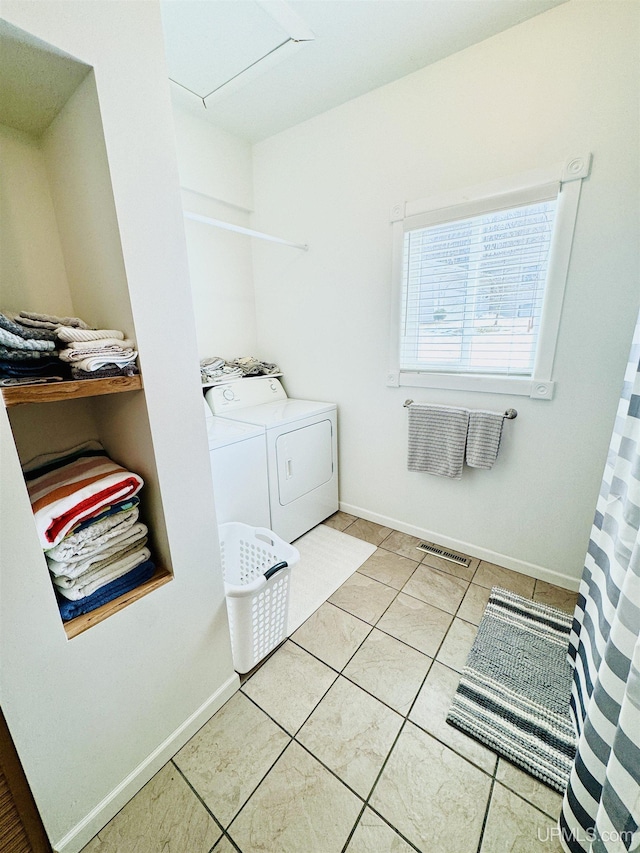 laundry room featuring washing machine and clothes dryer, visible vents, baseboards, light tile patterned floors, and laundry area