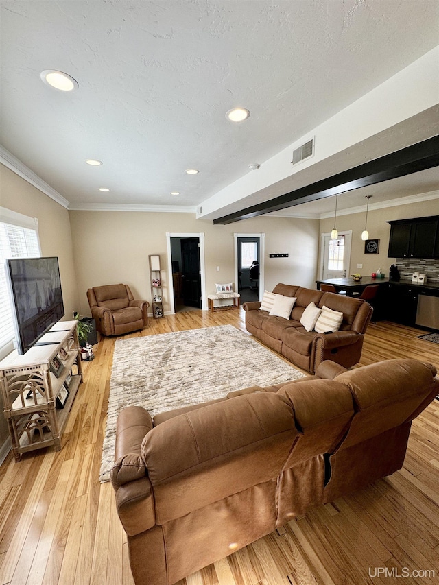 living area with visible vents, light wood-style flooring, recessed lighting, a textured ceiling, and crown molding