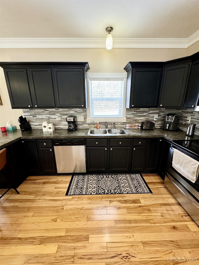 kitchen featuring a sink, stainless steel appliances, dark countertops, and light wood-style flooring