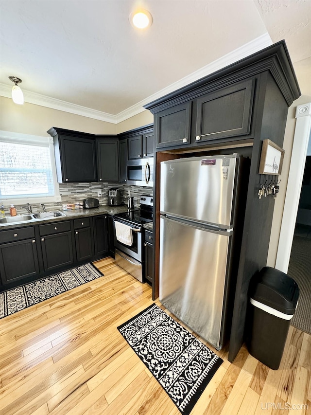 kitchen with a sink, stainless steel appliances, crown molding, and light wood finished floors