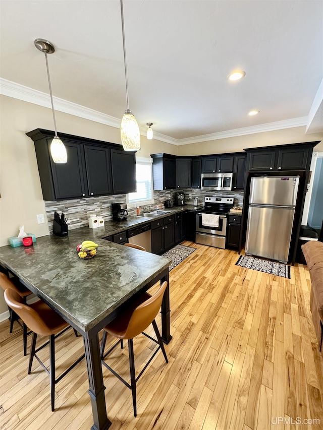 kitchen featuring dark cabinetry, light wood-type flooring, backsplash, and stainless steel appliances