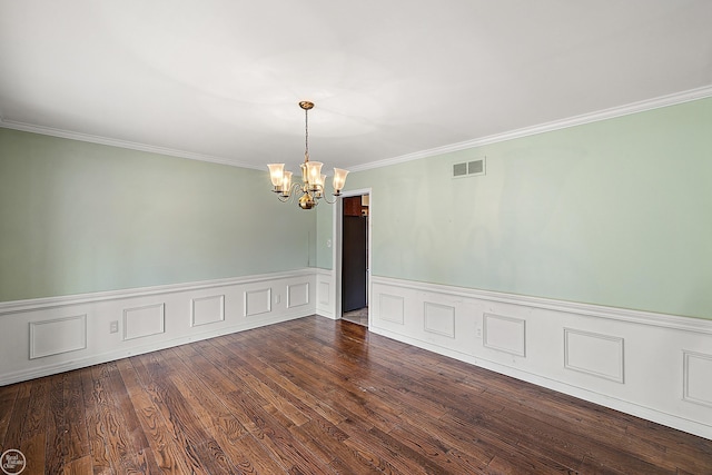 empty room featuring a wainscoted wall, visible vents, dark wood finished floors, crown molding, and a chandelier