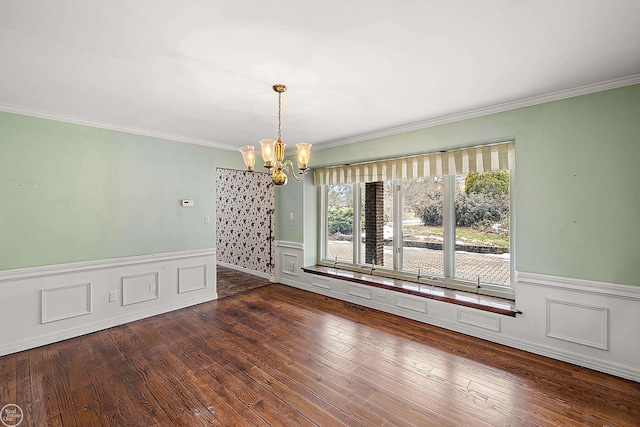 unfurnished dining area with a chandelier, dark wood finished floors, crown molding, and wainscoting