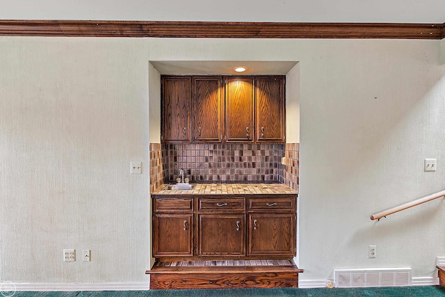 kitchen featuring visible vents, backsplash, dark brown cabinetry, light countertops, and a sink