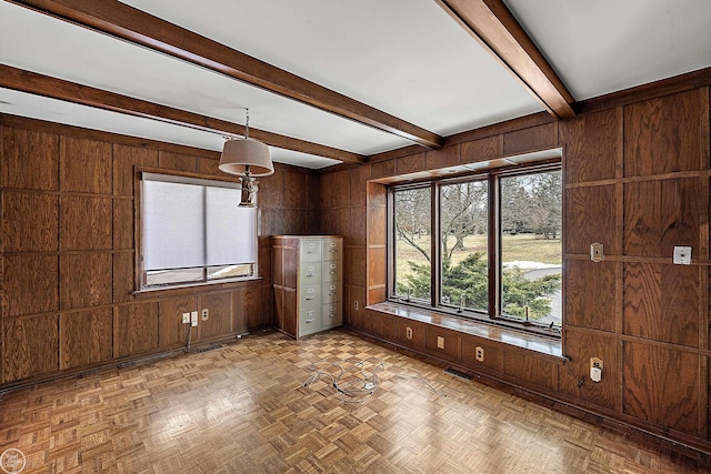 unfurnished room featuring beam ceiling, wooden walls, and visible vents