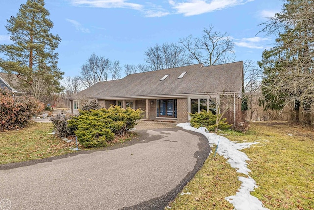 ranch-style home featuring brick siding, driveway, and a front yard