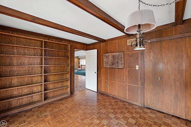 unfurnished room featuring beamed ceiling and wood walls