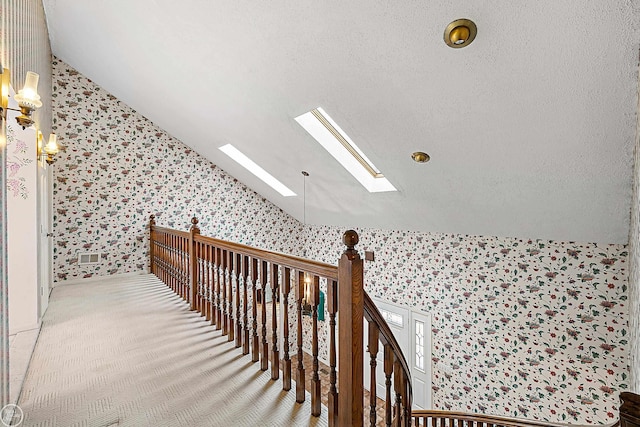 additional living space with carpet flooring, vaulted ceiling with skylight, a textured ceiling, and wallpapered walls