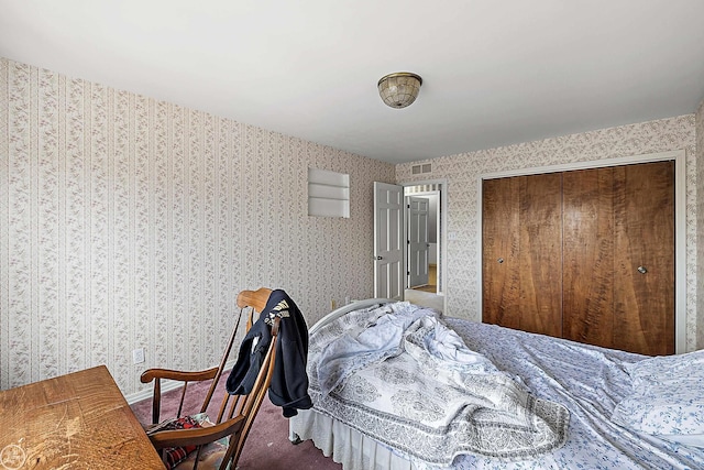 bedroom with a closet, visible vents, wallpapered walls, and carpet