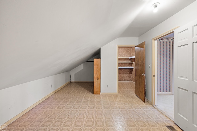 additional living space featuring lofted ceiling, baseboards, visible vents, and light floors