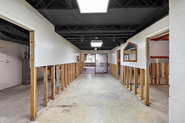 hall featuring concrete block wall and concrete flooring