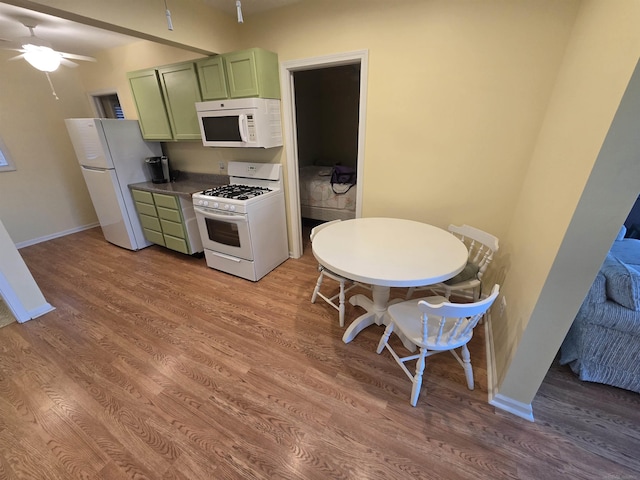 kitchen featuring green cabinetry, baseboards, white appliances, and wood finished floors