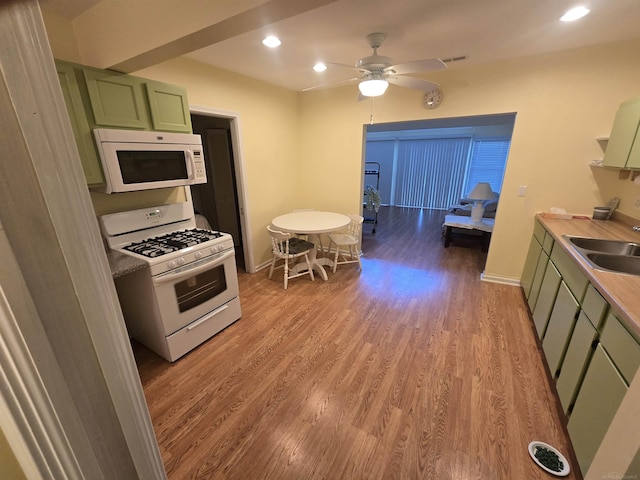 kitchen featuring green cabinetry, light wood-type flooring, white appliances, a ceiling fan, and a sink