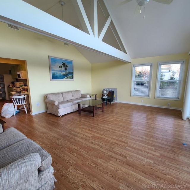 living area with visible vents, high vaulted ceiling, ceiling fan, and wood finished floors