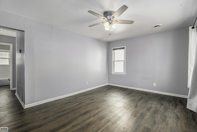 empty room featuring visible vents, baseboards, dark wood-type flooring, and ceiling fan