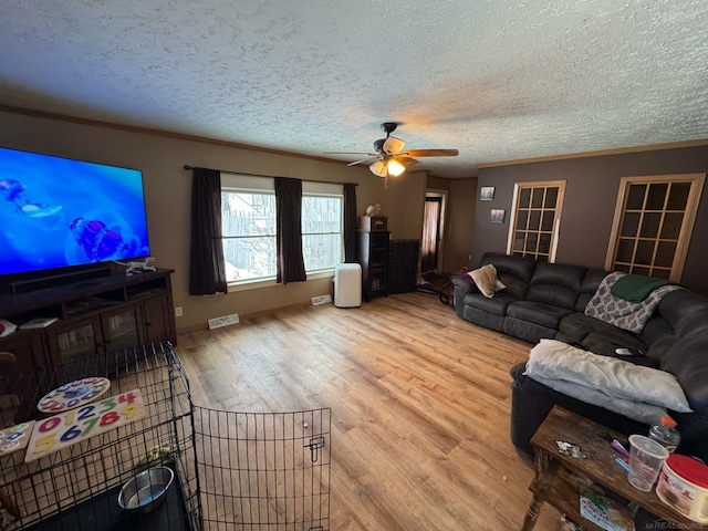 living room featuring ornamental molding, a textured ceiling, a ceiling fan, and wood finished floors