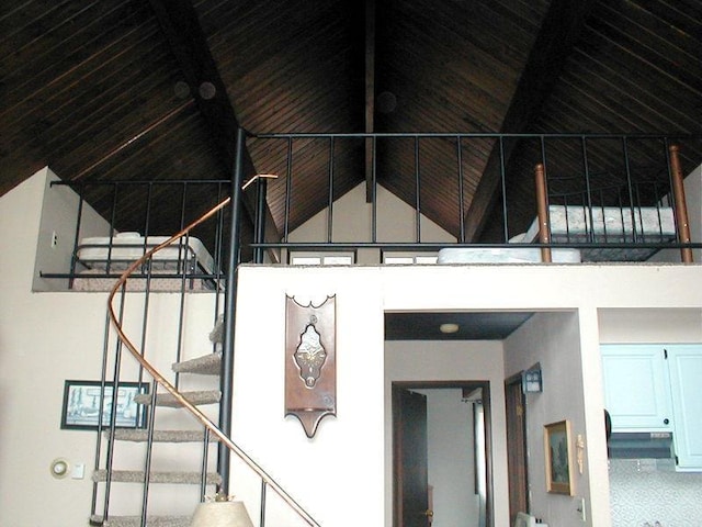 staircase featuring beam ceiling and high vaulted ceiling