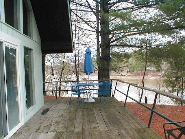 wooden terrace featuring outdoor dining space and a water view