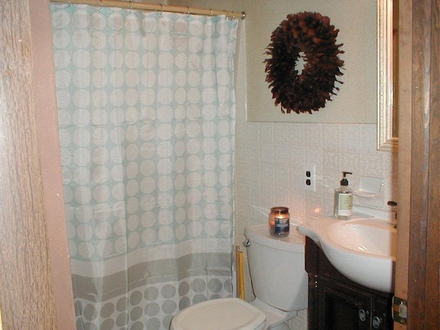 bathroom featuring toilet, curtained shower, vanity, and tile walls