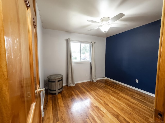 spare room featuring visible vents, baseboards, ceiling fan, and wood finished floors