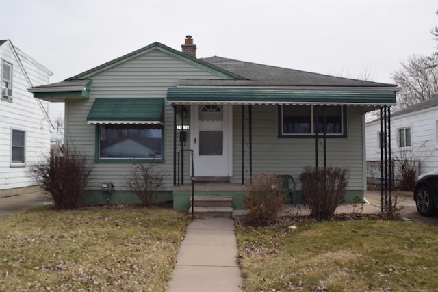 bungalow-style home with a chimney and a front yard