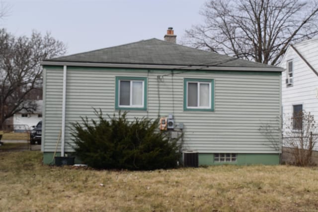 view of property exterior with central air condition unit, a chimney, and a yard