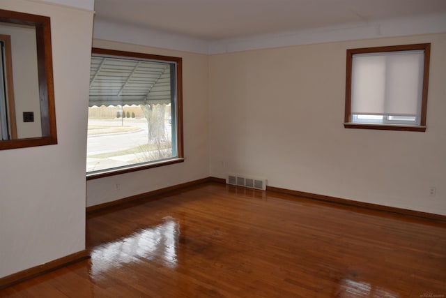 spare room with visible vents, baseboards, and wood finished floors