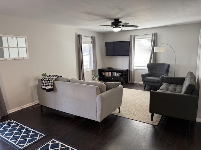 living area with dark wood finished floors, visible vents, baseboards, and a ceiling fan